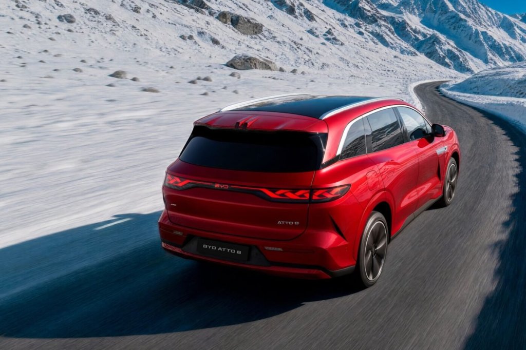 BYD Atto 8 rossa vista da dietro mentre percorre una strada di montagna tra la neve