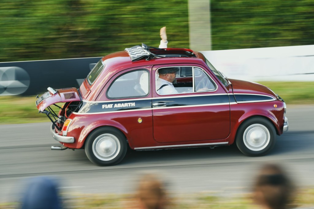 Una Fiat 500 Abarth rossa in corsa durante un evento storico