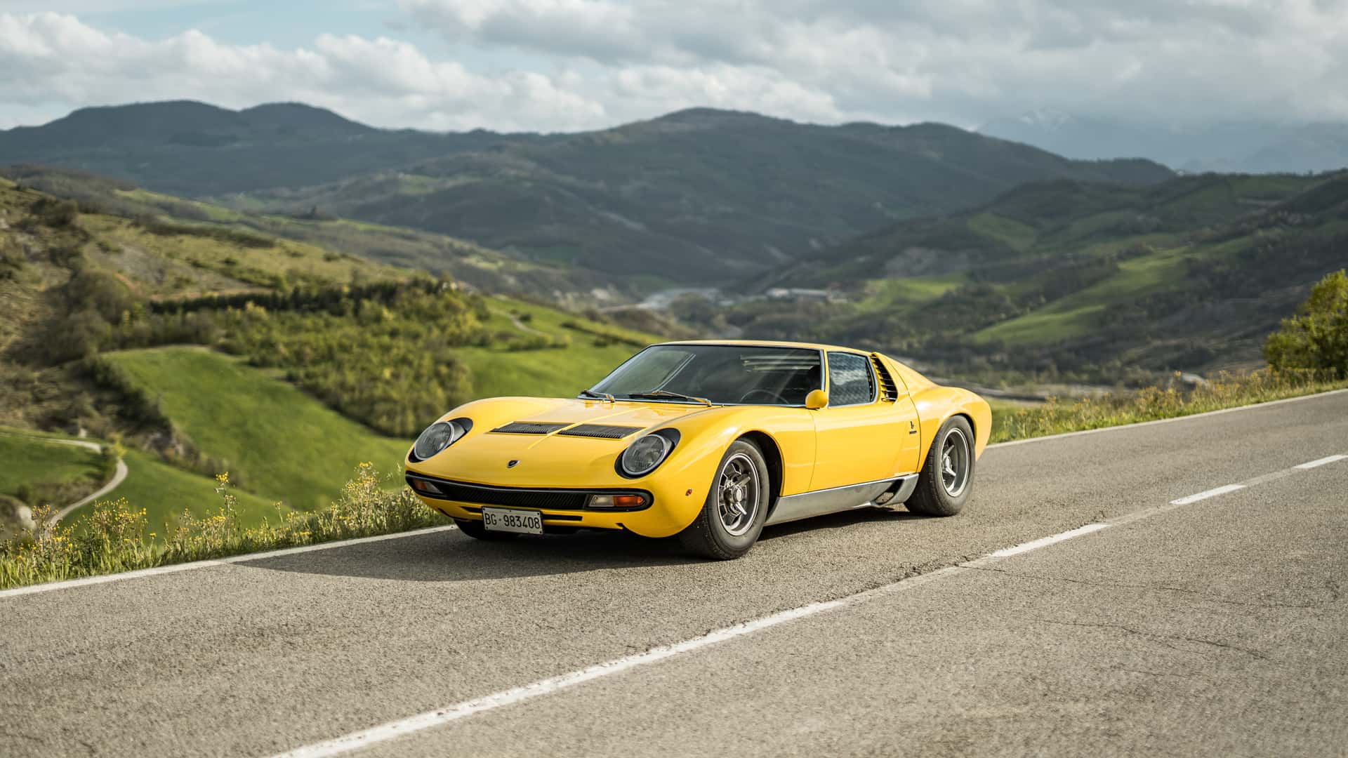 Una Lamborghini Miura SV gialla su una strada di collina