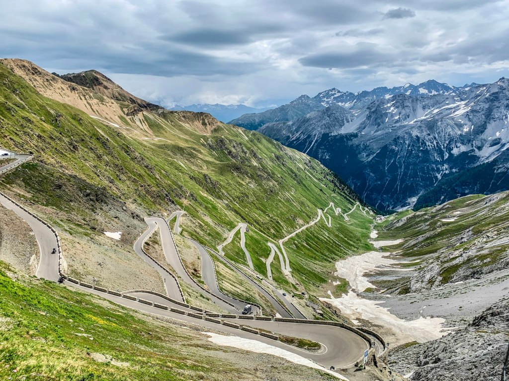 I tornanti del Passo dello Stelvio tra le montagne verdi sotto un cielo nuvoloso